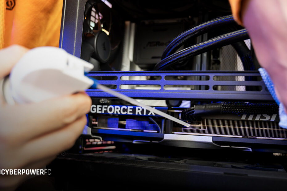 A man using an air duster to remove dust from the inside of his RGB gaming PC.